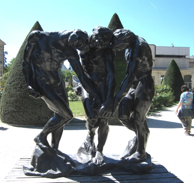 three bronze statues standing in front of a tree