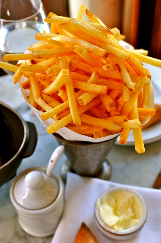 small bowl of french fries next to two cups and spoon