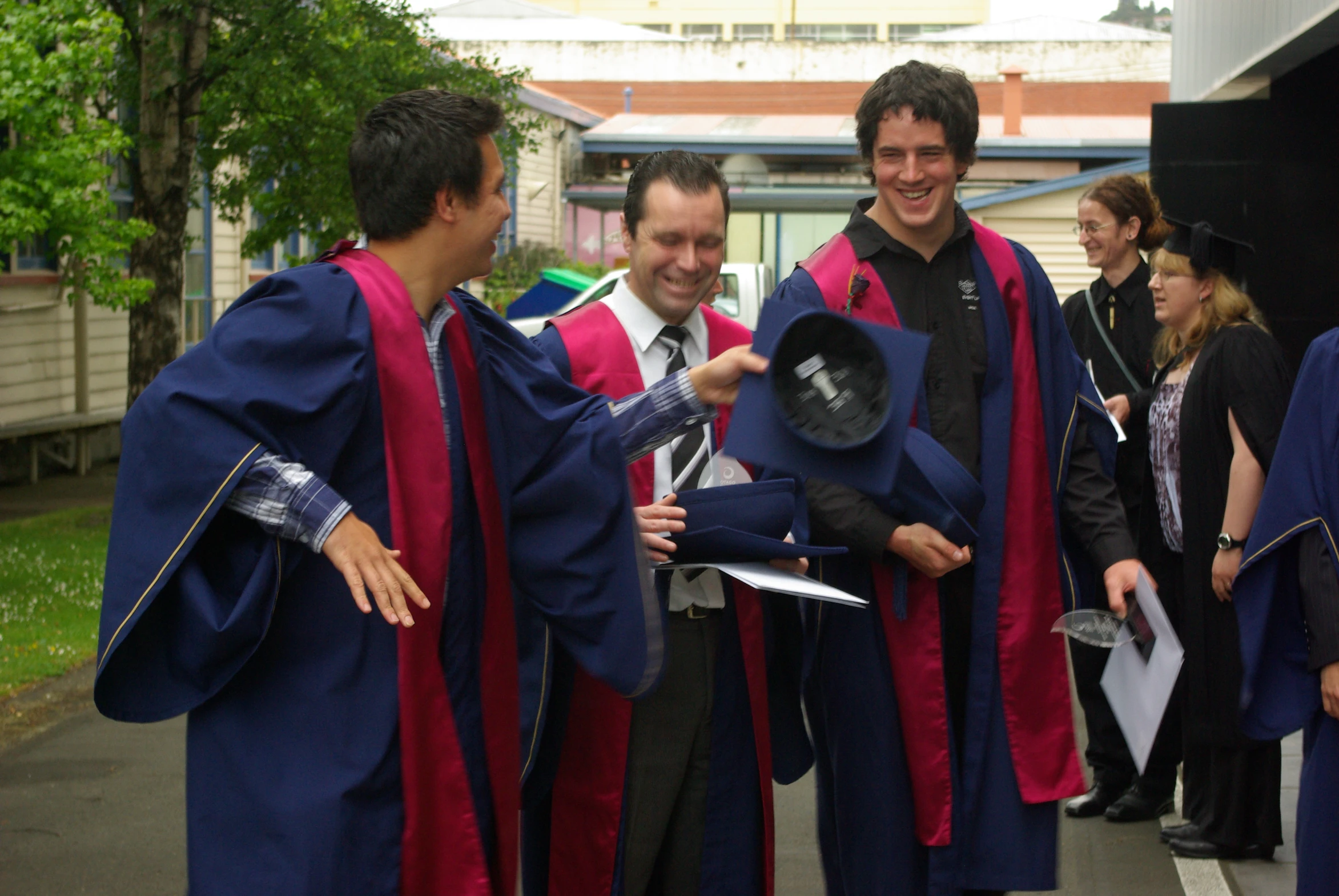 a group of men and women wearing graduation gowns, laughing