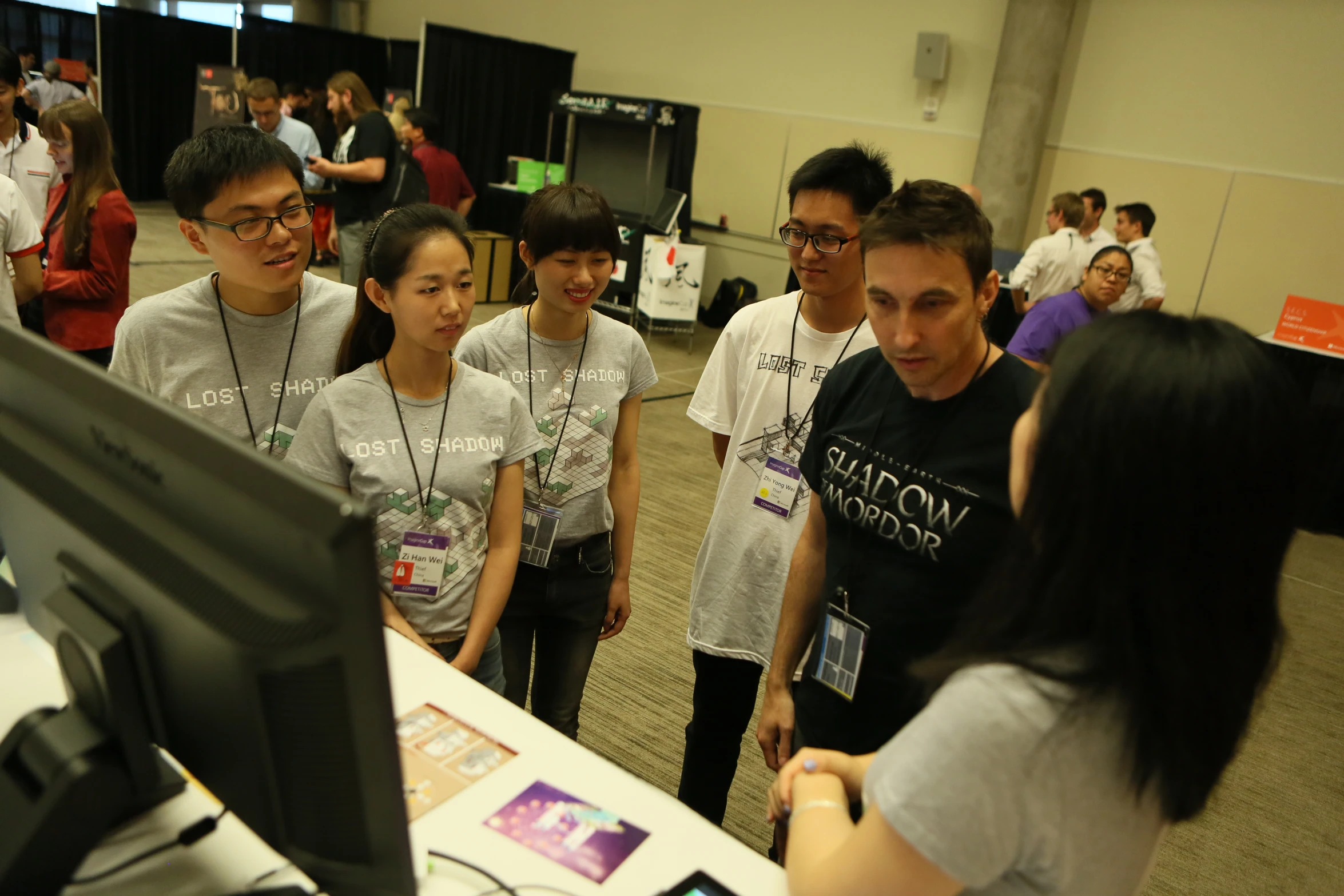 several people stand and look at a computer screen