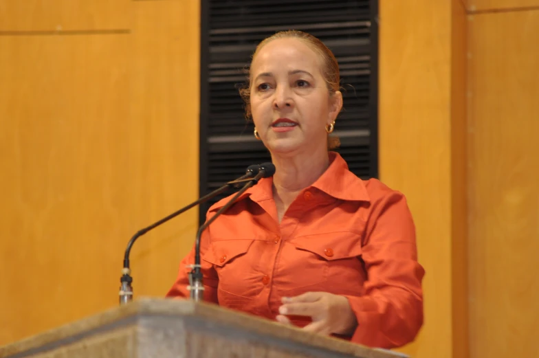 a woman standing at a podium talking into a microphone