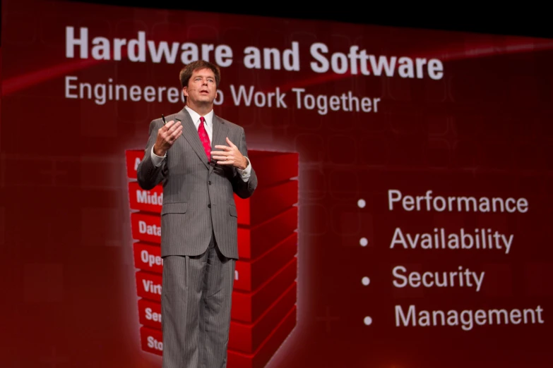 a man in business attire standing on stage talking