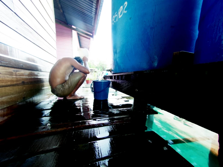 a person crouching in the rain with a cup