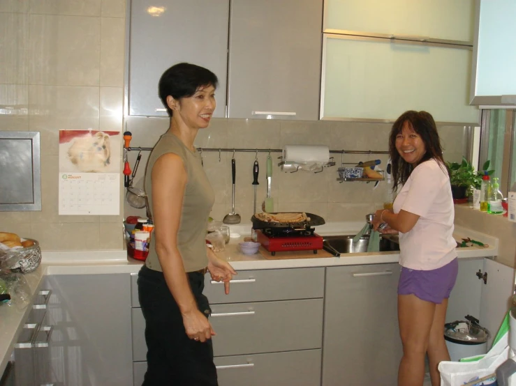 two young women smiling and standing in the kitchen