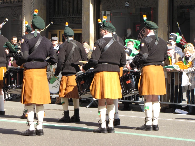 men in orange kilts are performing for a crowd