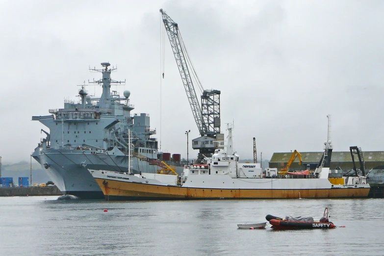 two tug boats in the water next to a boat with a crane on it