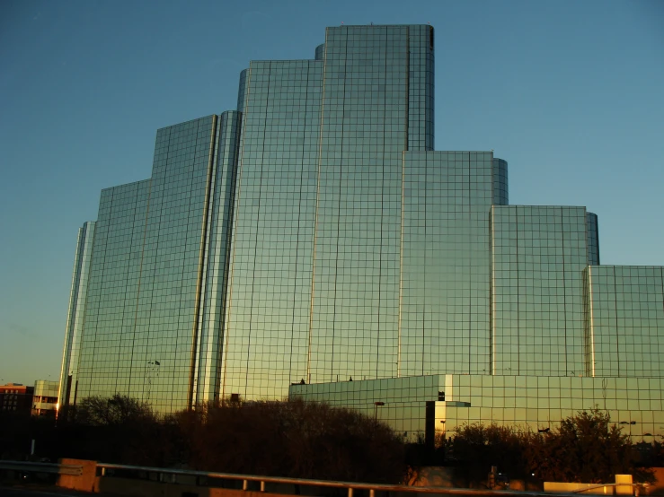 a glass building near a body of water with trees below