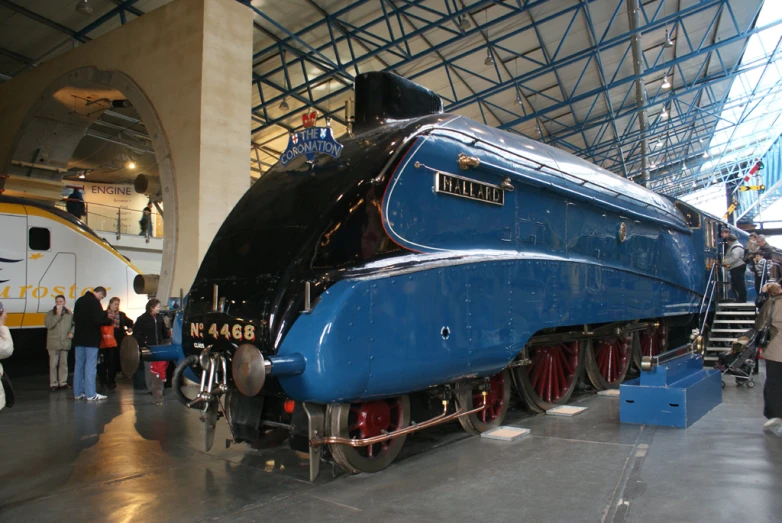 blue train displayed in an indoor area with people around it