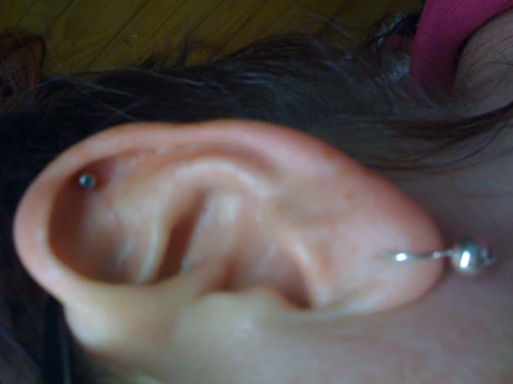 a person wearing a silver ear cuff with an empty piece of jewelry hanging out of it