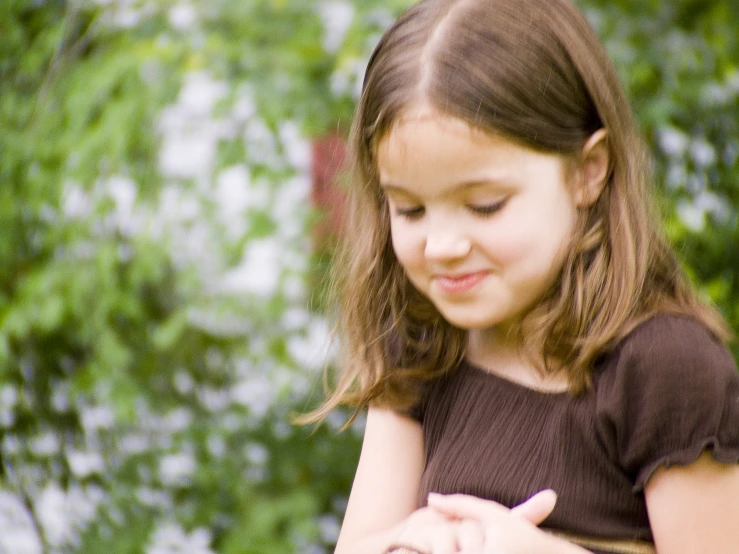 a girl in the grass holding a cell phone