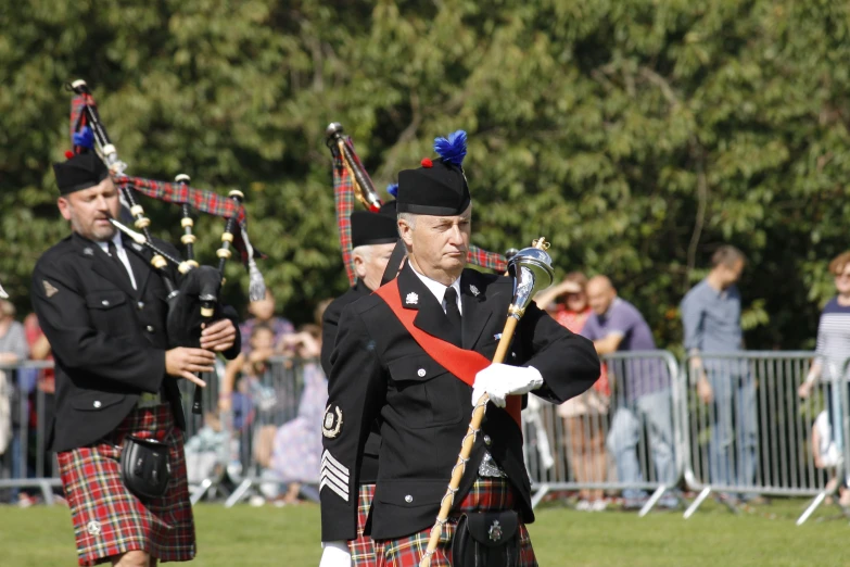 a man wearing an black uniform and holding two sticks