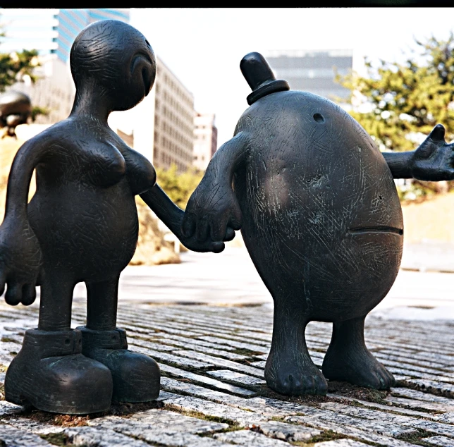 two statues of a boy and a girl, one holding hands