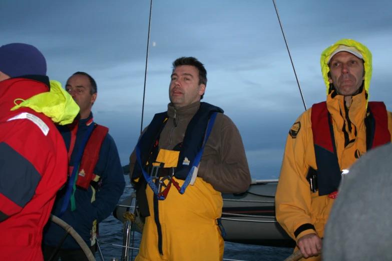 a group of men in yellow and red standing next to each other on a boat