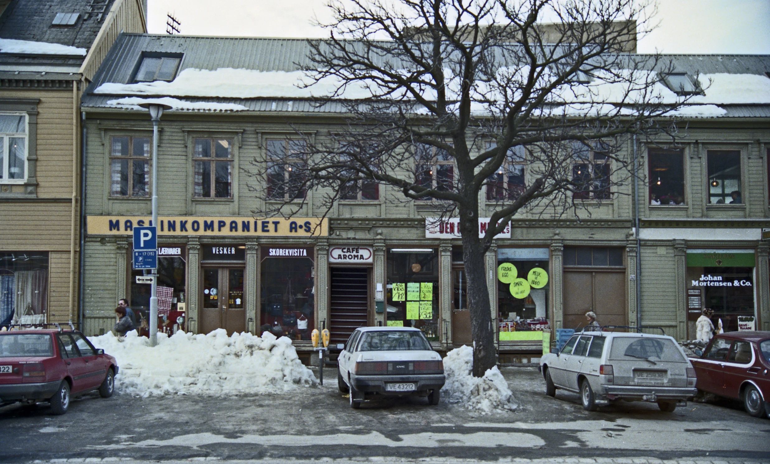 a city street with cars parked outside and snow on the ground