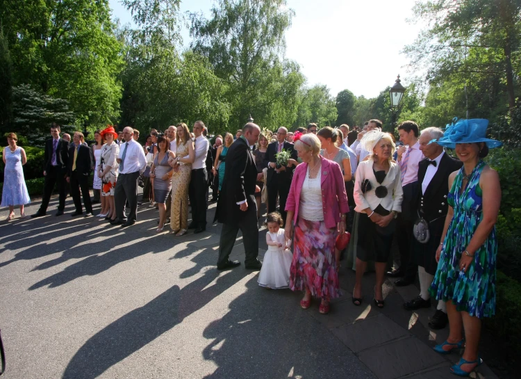 a crowd of people wearing fancy clothes standing near trees