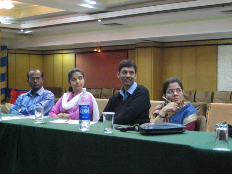 five people sitting at a table with a laptop