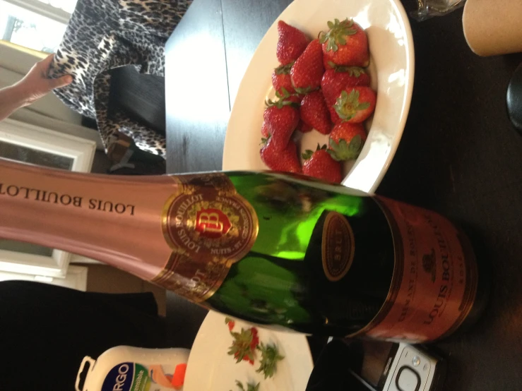 a bottle of sparkling sparkling wine next to strawberries