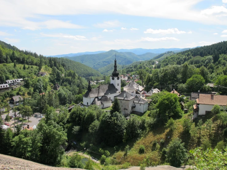 an old church with a steeple surrounded by trees in the mountains