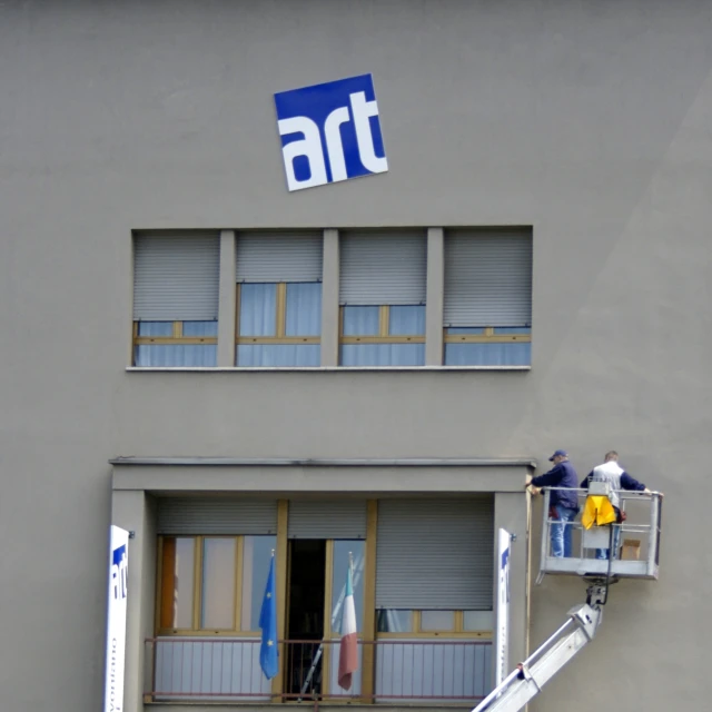 two men are painting a building on the outside