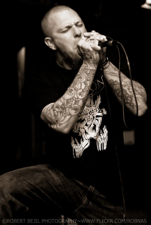 man in black shirt blowing up his fist while singing