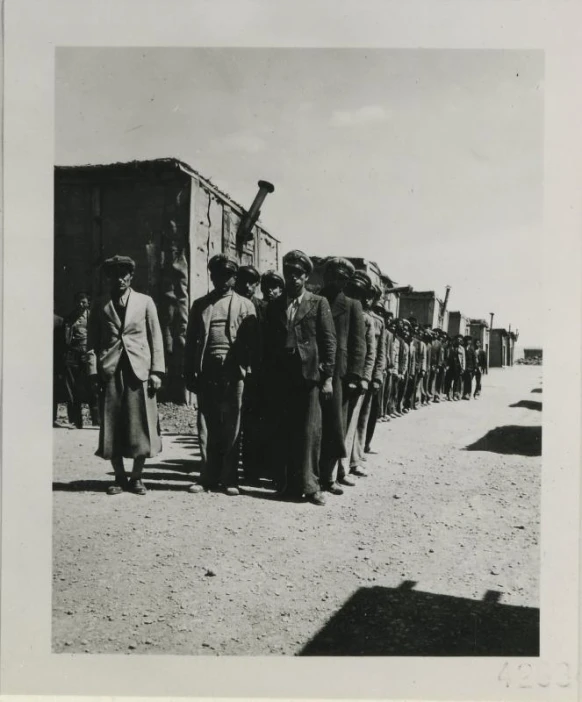 a black and white pograph of people near trucks