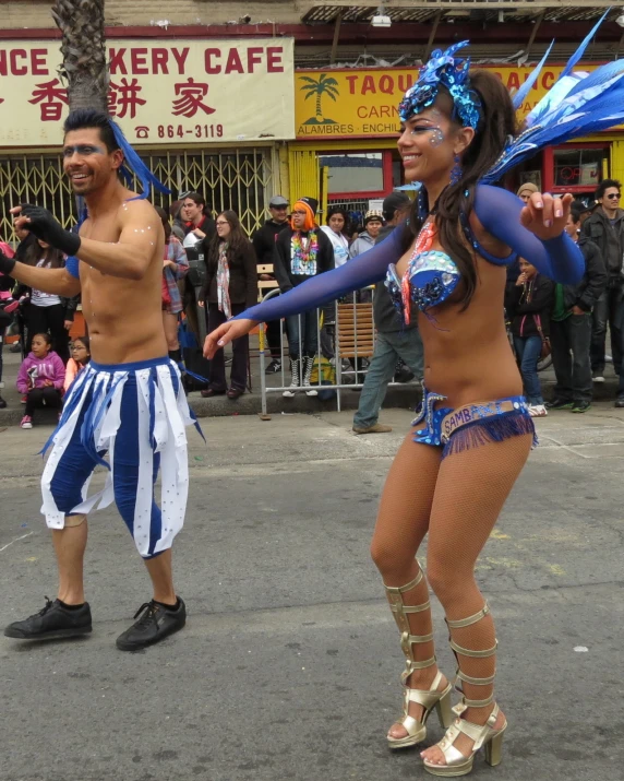 two dancers in blue and white outfits standing near other people