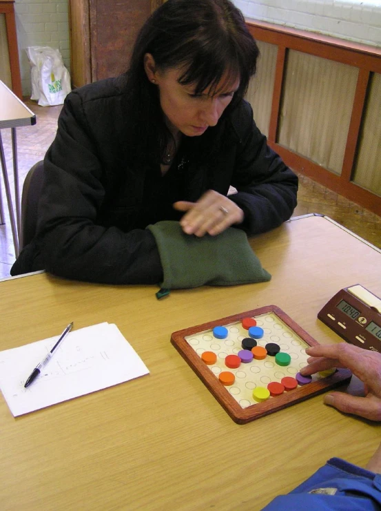 woman decorating small wooden game board with ons