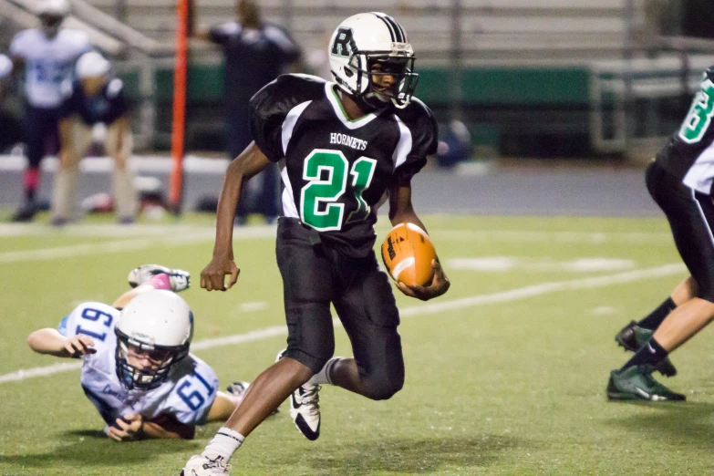 a player running with a football while another is behind him