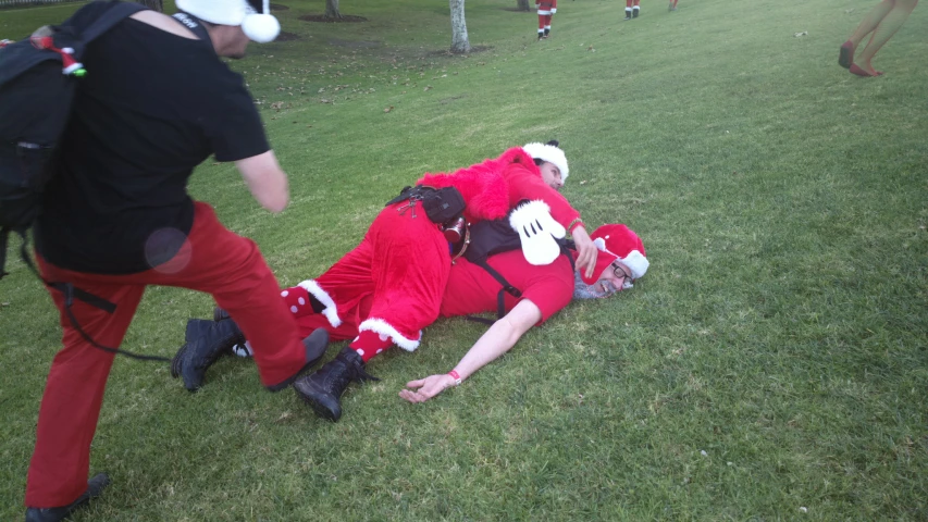 two people in santa suits are in the grass