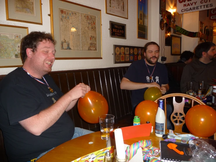 people are sitting at a bar with orange and white balloons