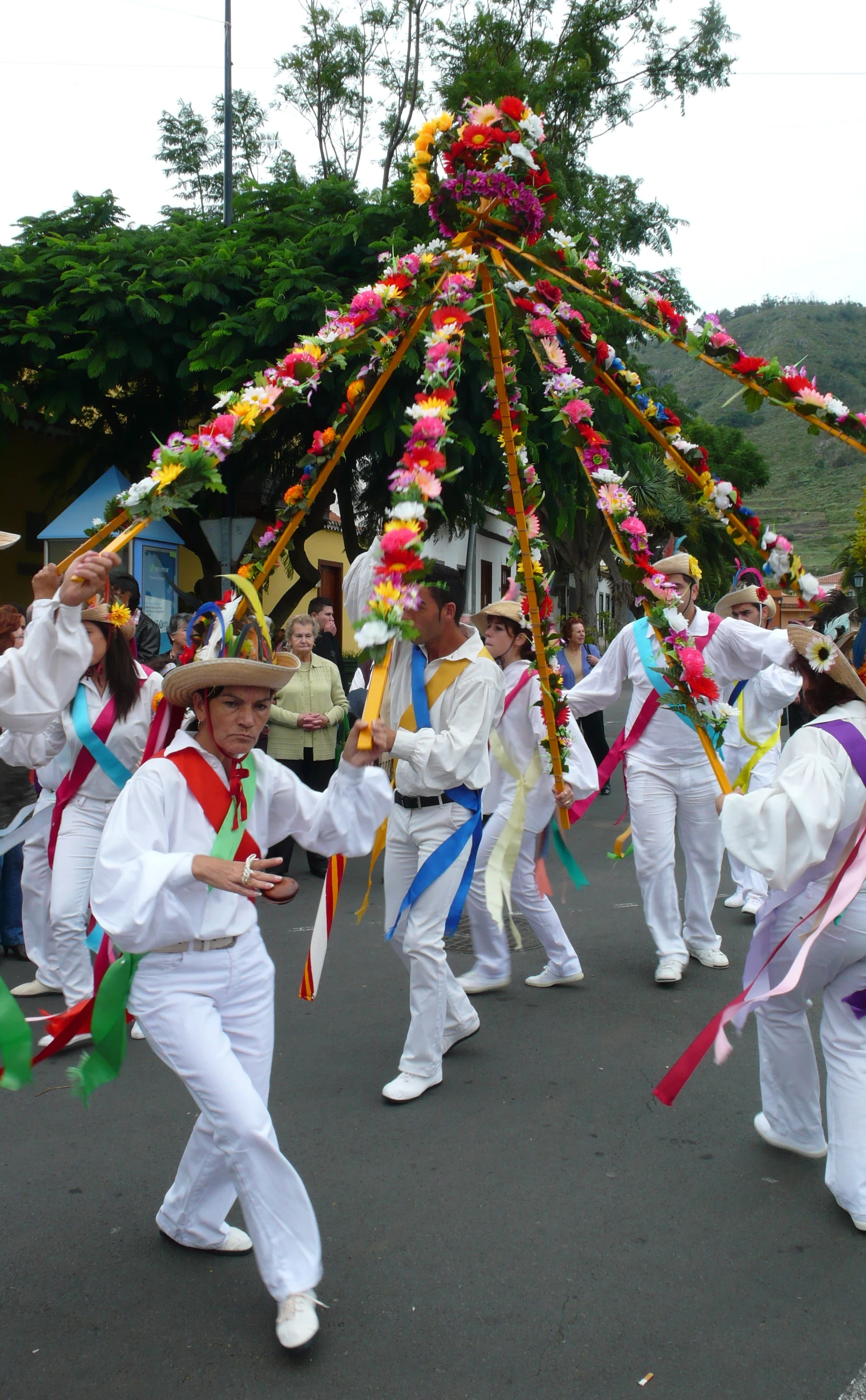 several young people in white are walking around with colorful streamers