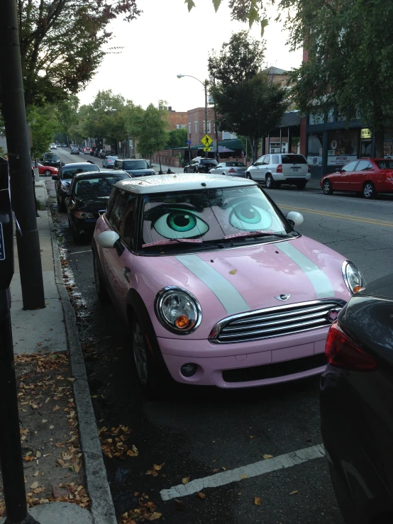 a pink car parked on the side of the road with one eye in it