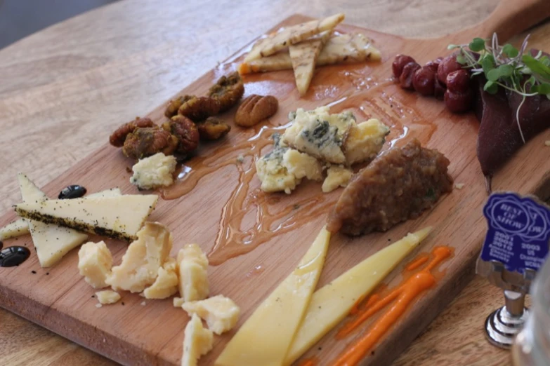 some cheeses and various kinds of meat on a wooden  board