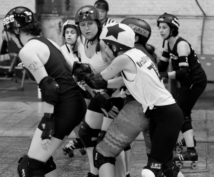 women in protective gear playing ball on pavement