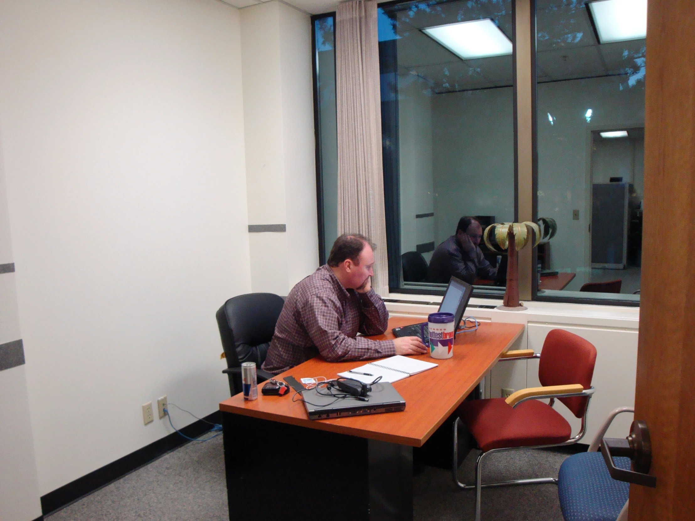 two people sitting at a desk with laptops