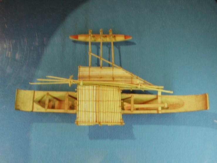 an elaborate wooden model of a boat with bamboo rafts