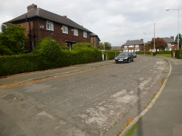 a car is driving down a road next to a house