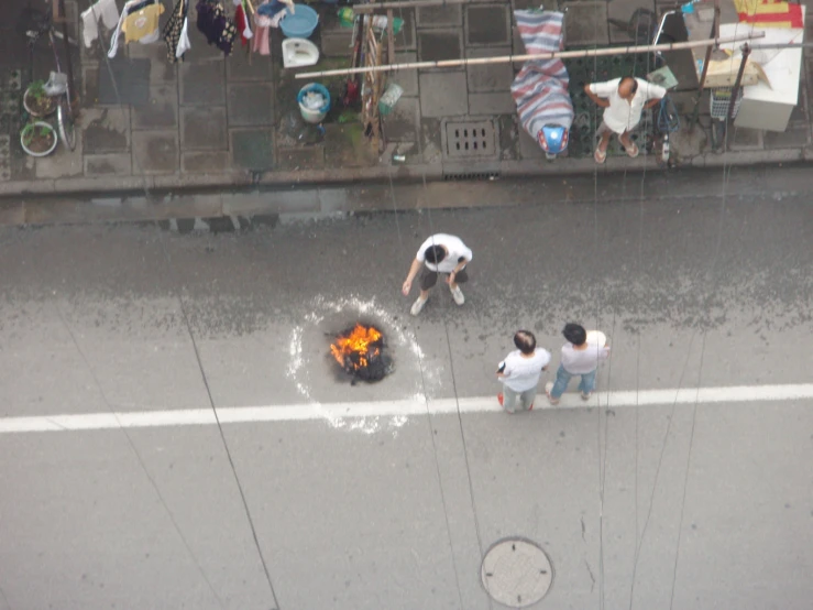 people stand around an open fire in the middle of a street