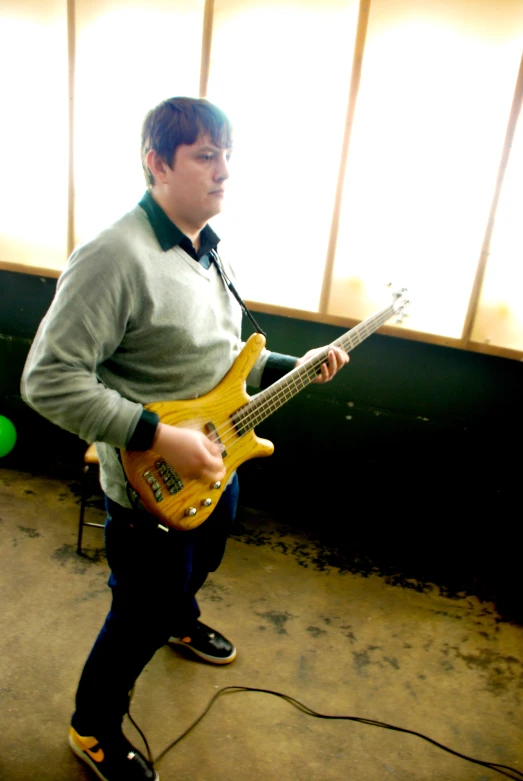 a man holding a bass guitar while standing on a tiled floor