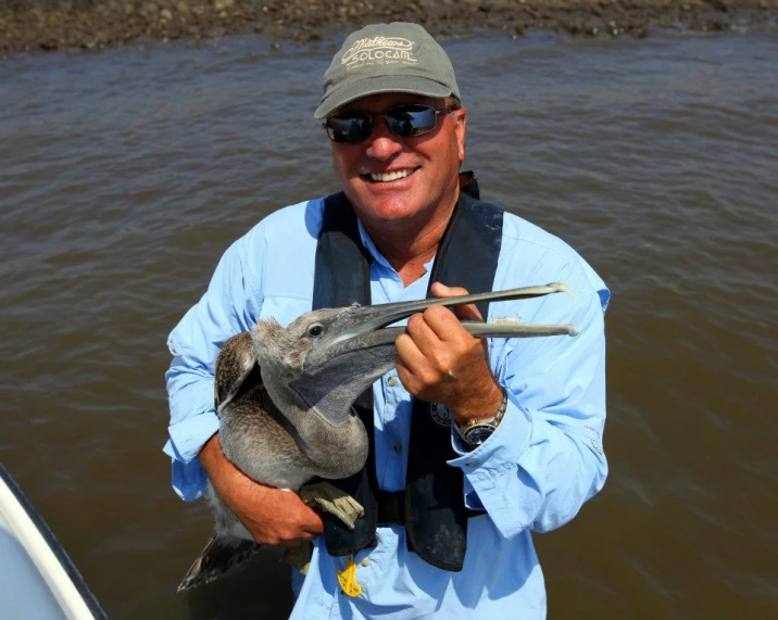 a man holding onto a baby animal inside a boat