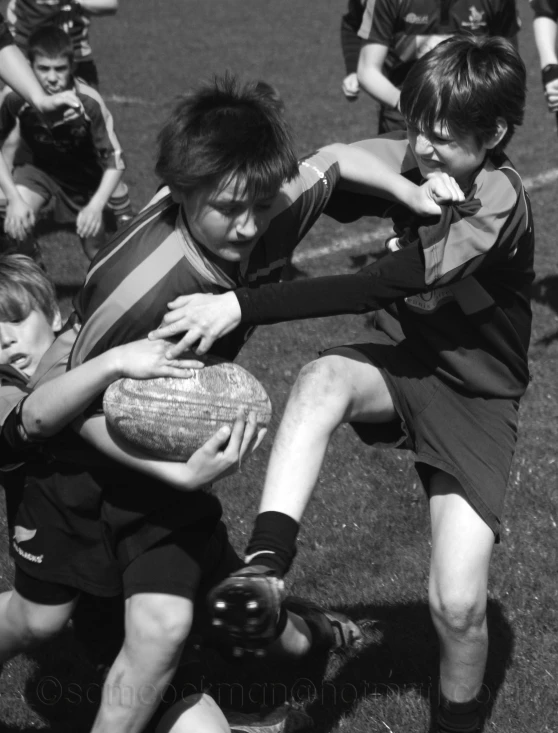 two boys are holding onto an older boy's ball