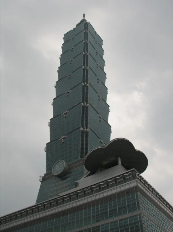 a clock on top of a skyscr with clouds in the background