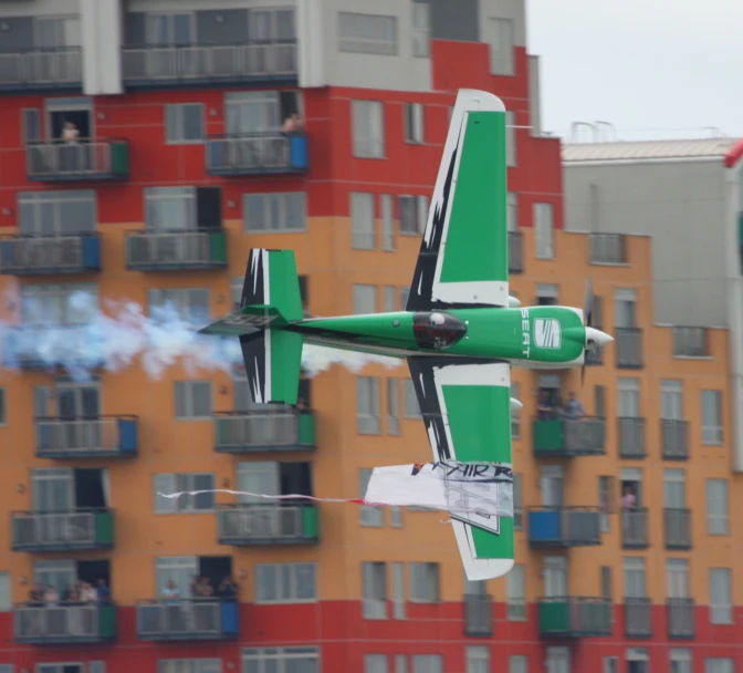 a green and white plane in front of a multi - story building