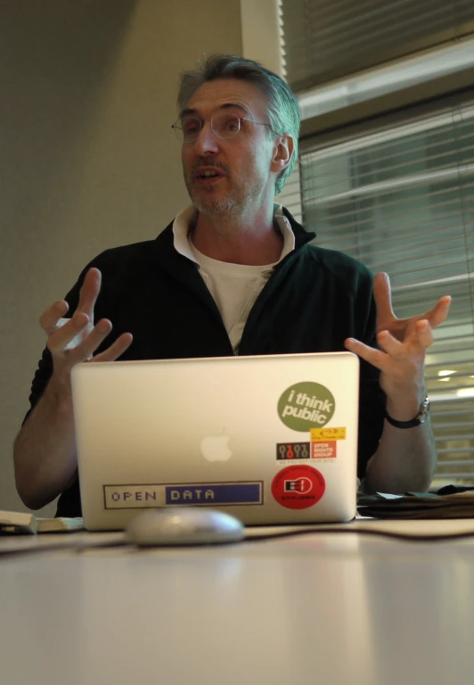 a man sitting at a table with an apple laptop in front of him