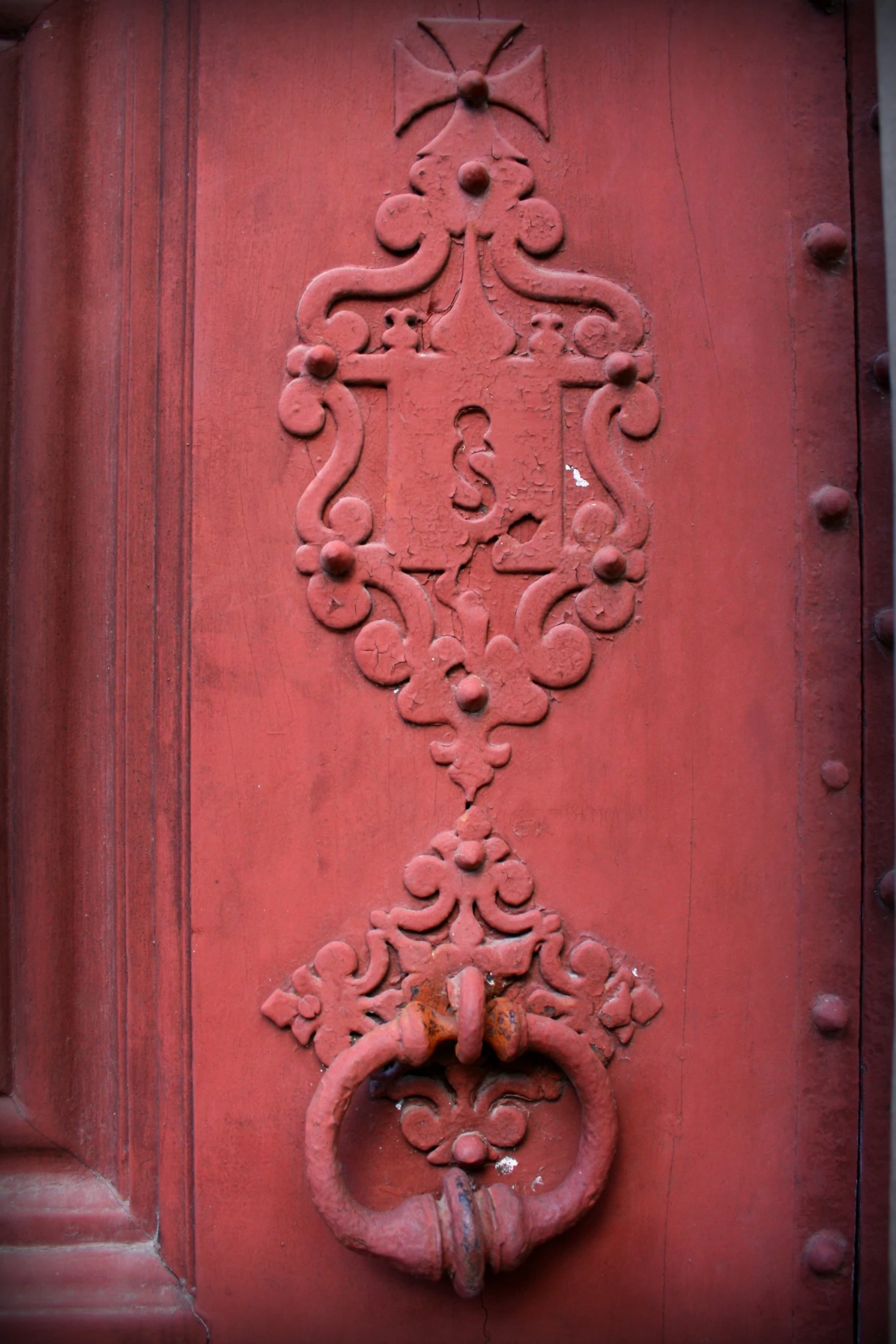 an ornate door handle on a red stuccoed building