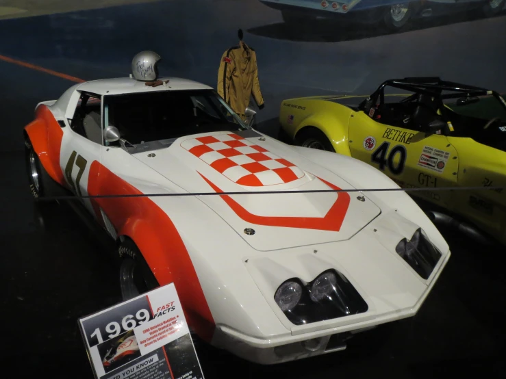 two old sports cars on display in a museum