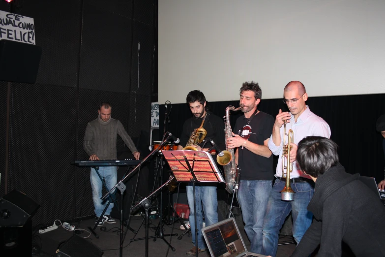 four musicians playing musical instruments and a screen behind them