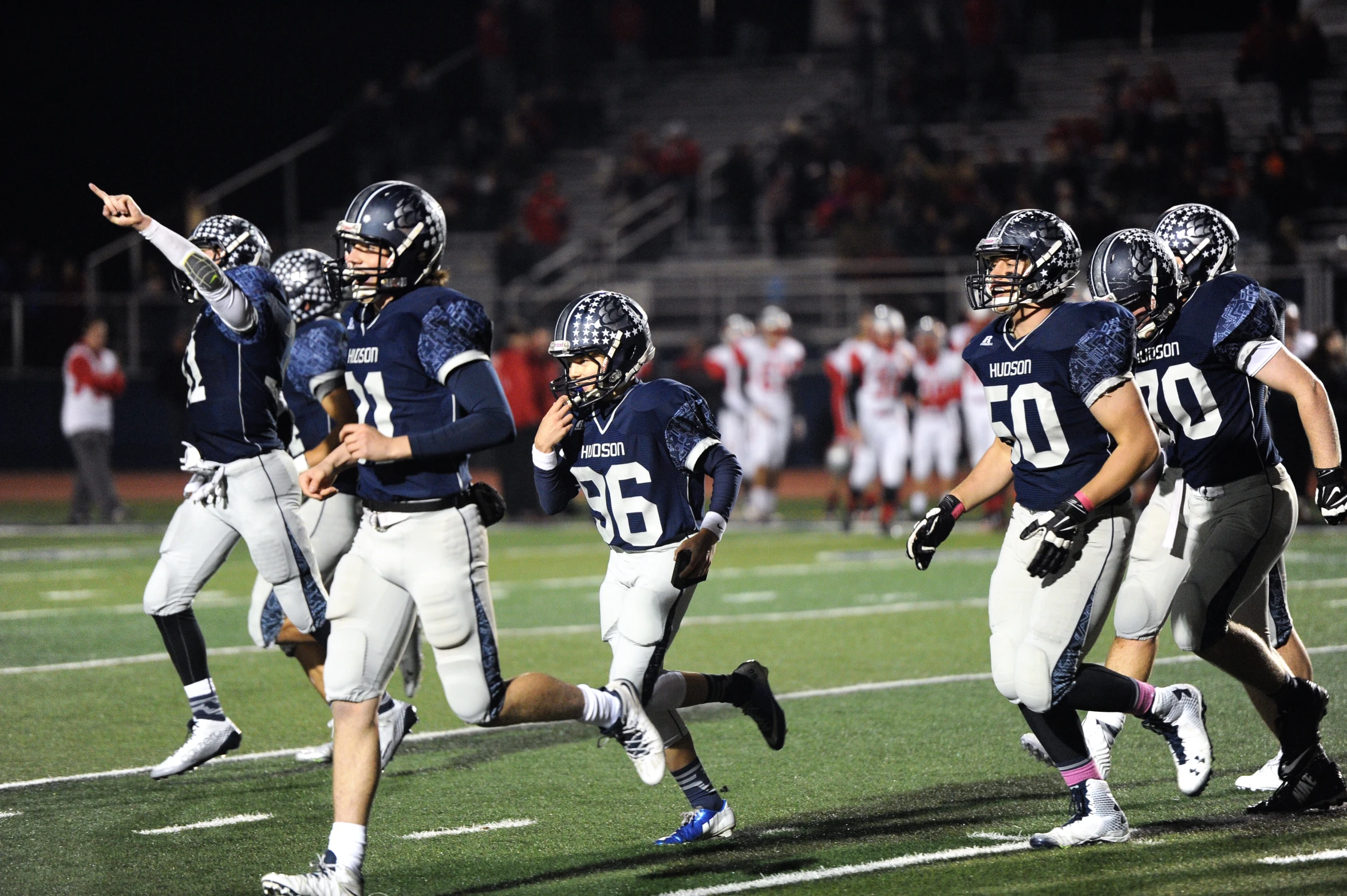 a football team running on the field with one of their players looking to the sidelines