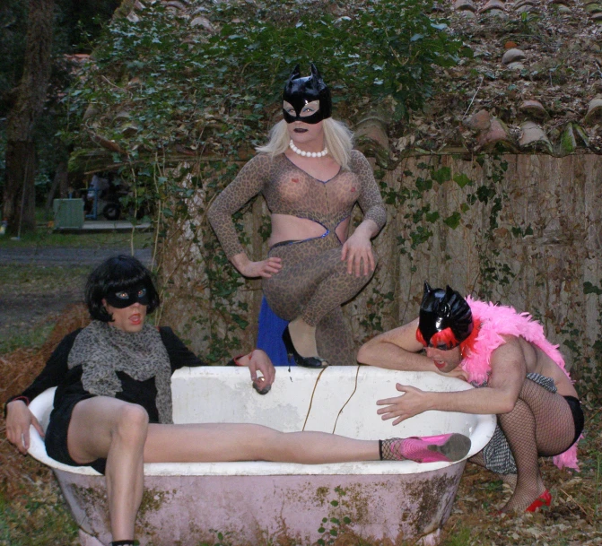 three  women wearing catsuits take a bath in an old fashioned bathtub
