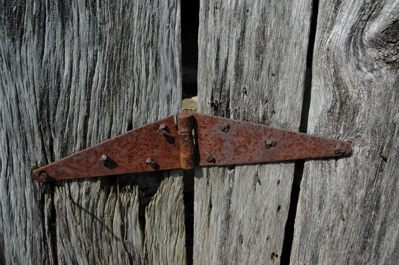 the rusted triangle is attached to the wooden board